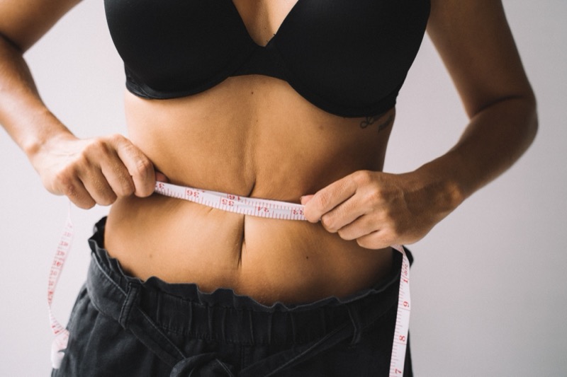 Mains mesurant un tour de taille avec un mètre ruban