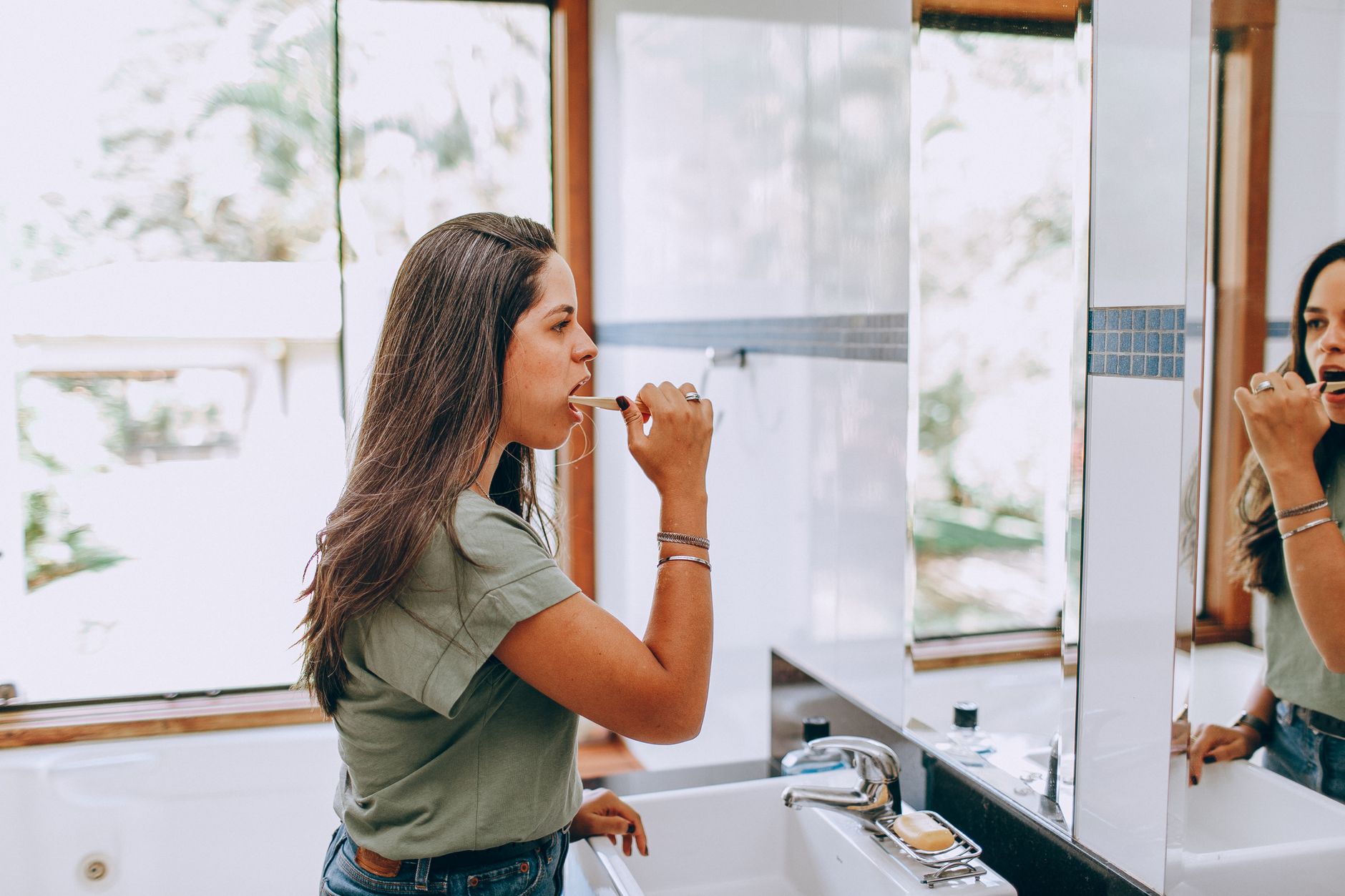 Femme se brossant les dents dans une salle de bain lumineuse, moment calme d'une routine du matin