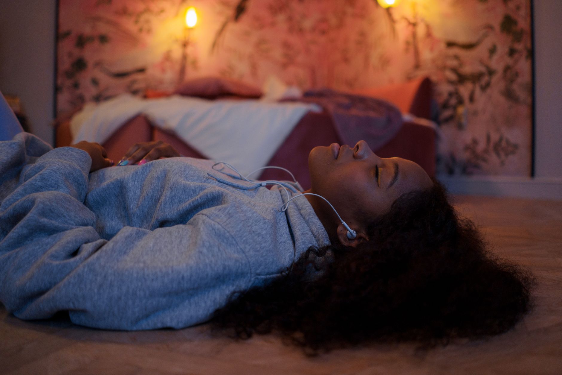 Femme allongée au sol dans une chambre tamisée éclairée à la bougie, détendue le soir avant de dormir