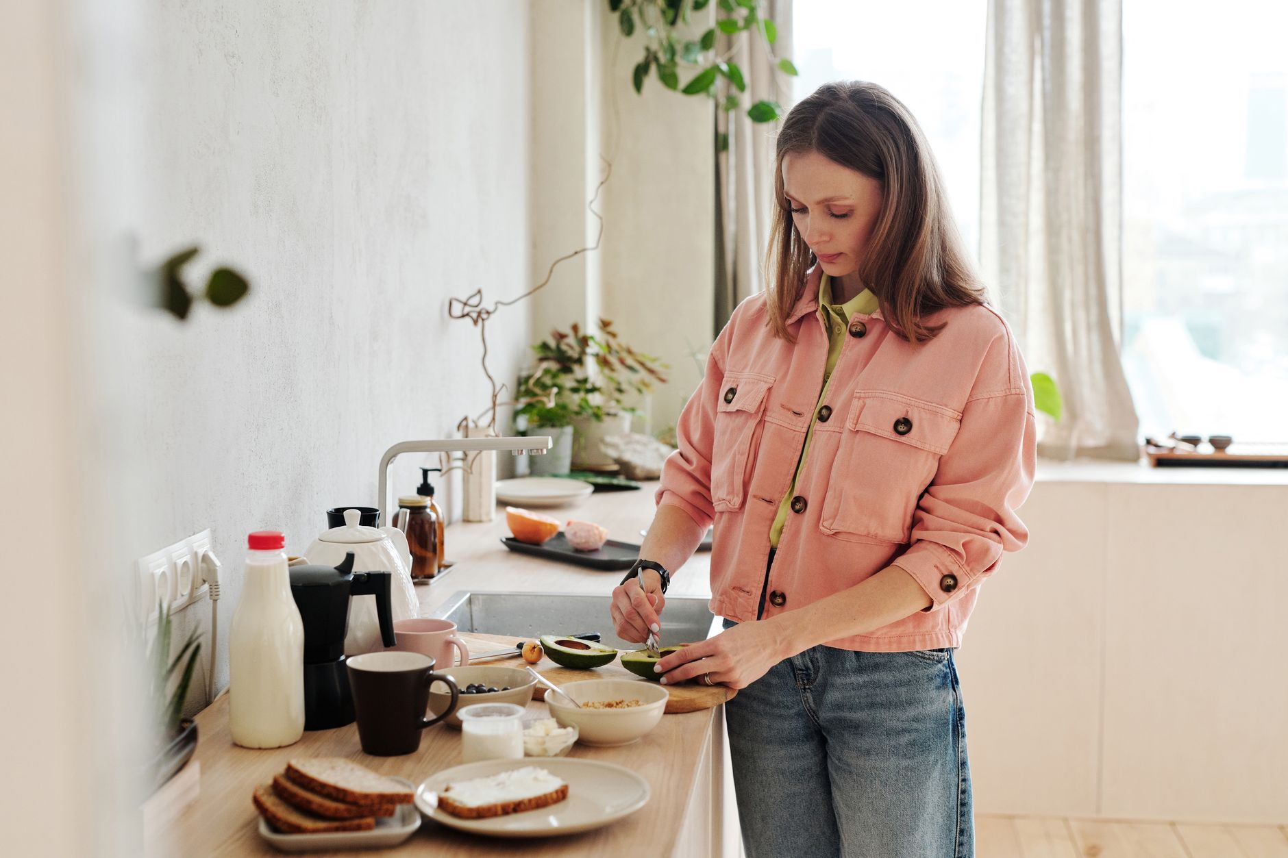 Jeune femme souriante préparant une salade colorée dans une cuisine lumineuse, entourée de légumes frais